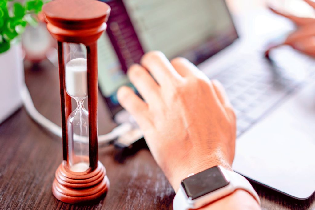 man typing with hourglass carving the writer’s block